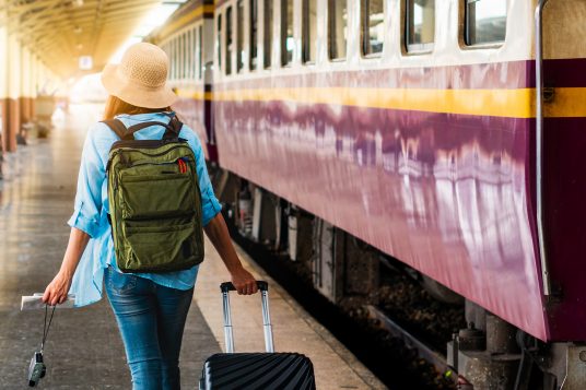Sustainable traveler: Solo woman backpacker traveler plan safety trip low cost budget summer holiday after coronavirus. Empty tourists on train railway platforms. Use bus train sustainable environmental friendly transport