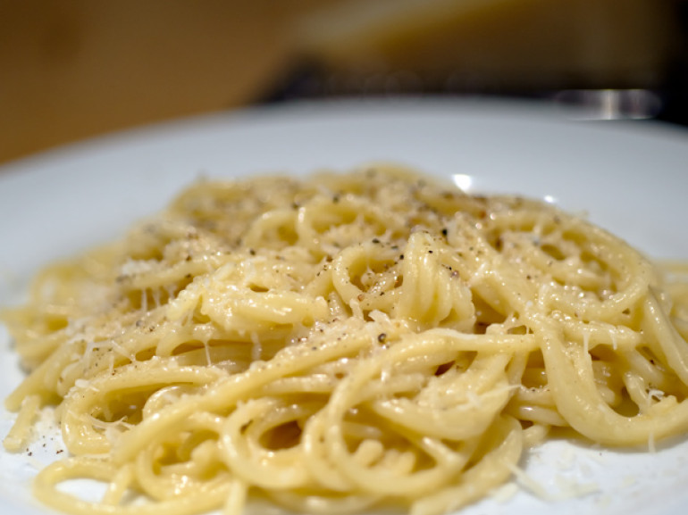 a plate of spaghetti with cheese and pepper souce