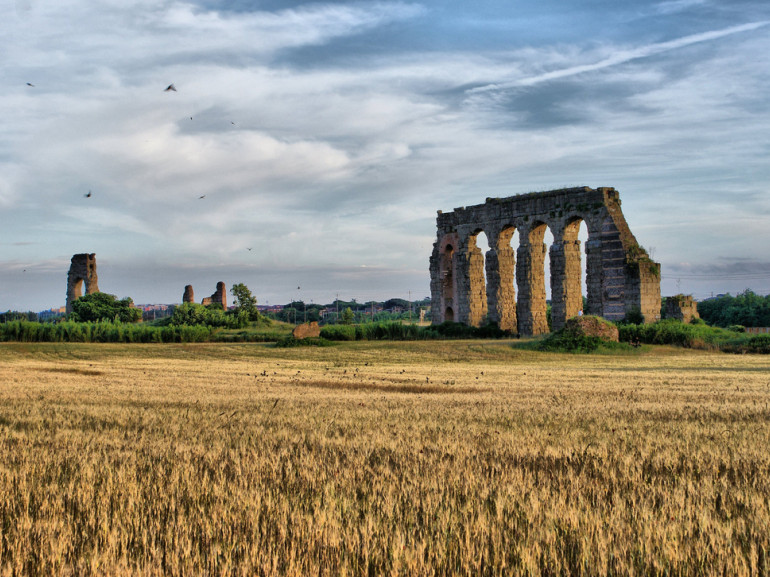 in a field, the rest of a roman aqueduct made of stones