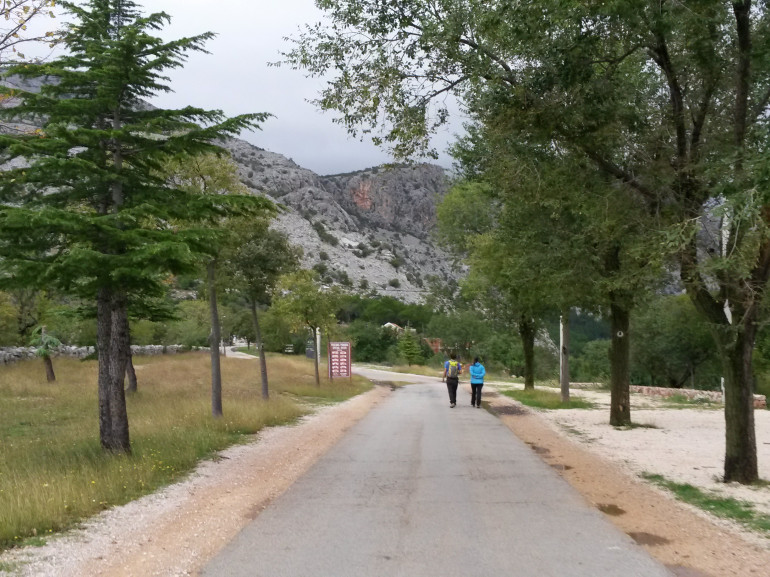 two people walking on the path towards the park. On the background you can se mountains