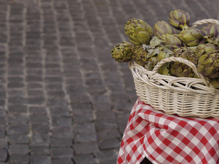 a basket full of artichockes on a table on the street