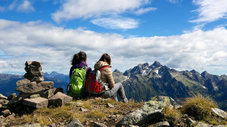 Two girl on the top of the mountains watching at the horizon, where you can see Cima d'Asta