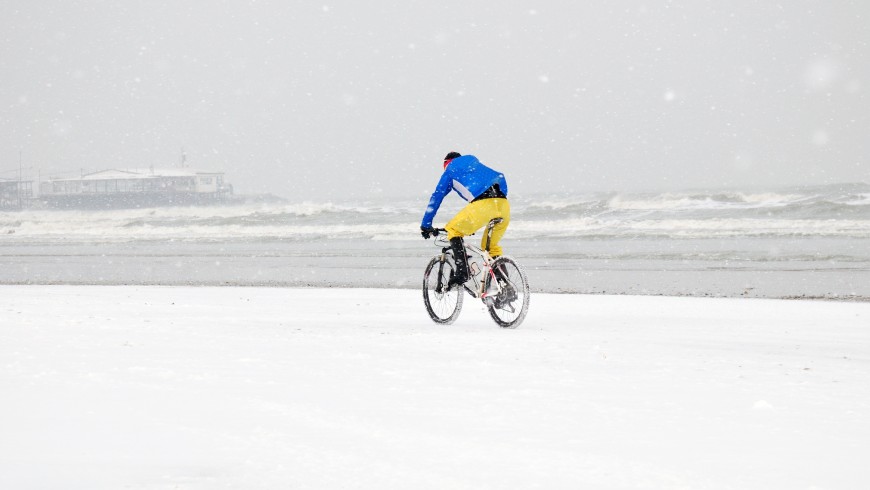 person with bike in the snow storm on the beach