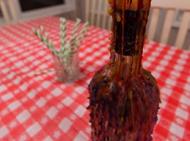 Wax candle with a burning flame at the top of an empty bottle