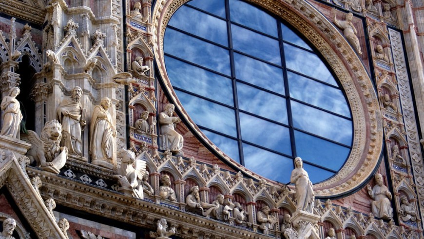 The rose window of the Duomo in Siena. The glass wall reflects the sky