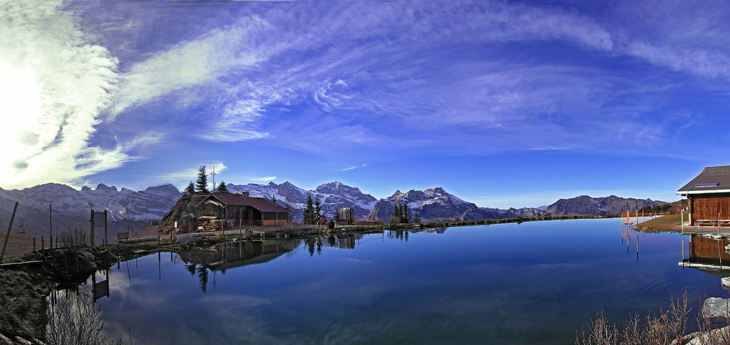 The Härzlisee lake reflects the sky (Switzerland); on the background, a mountain chain coverd with snow