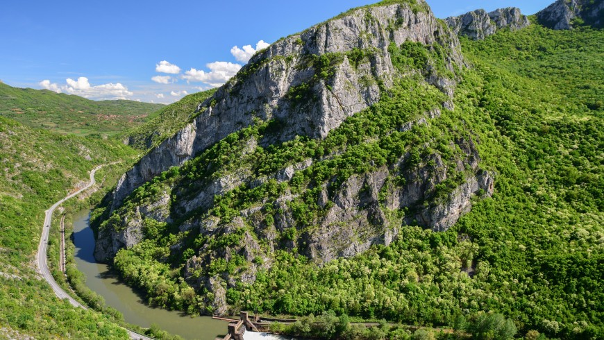 rocky peak with trees and a river in the valley
