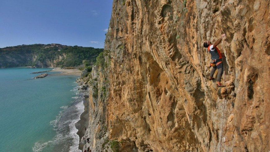 a guy climbing a red wall on the sea