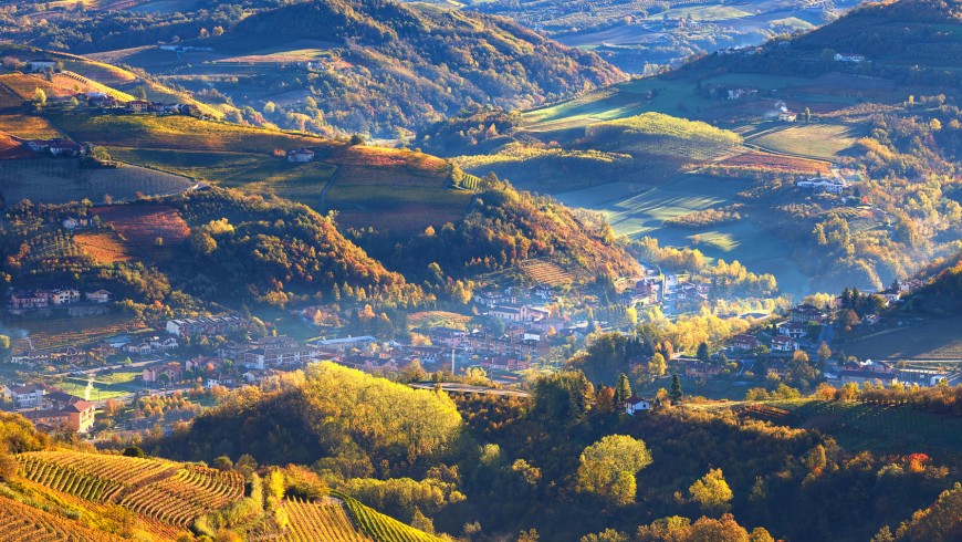 During the truffle festival, foggy morning over small town among autumnal hills and vineyards of Piedmont, Northern Italy (view from above).