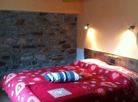 One of the rooms from the hotel, with red blankets and stone walls