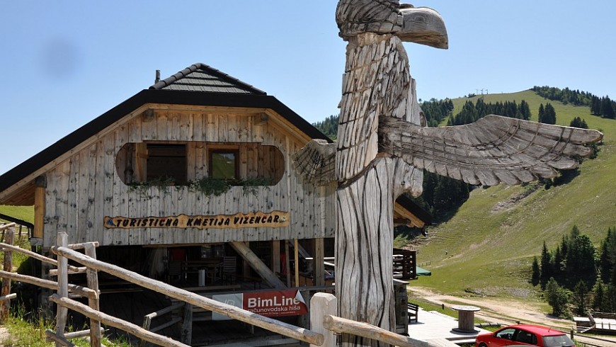 facciata dell'hotel con totem in legno e montagne in sottofondo