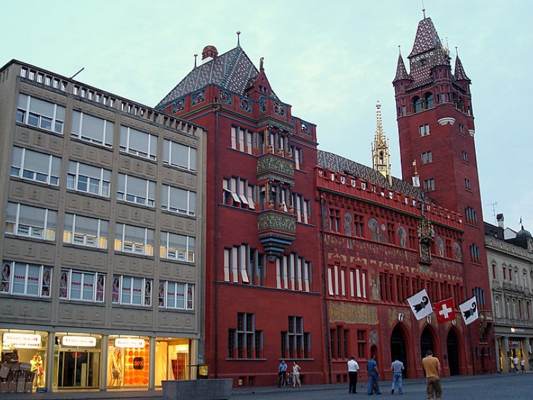 a red decorated building with a tower surrounded by other buildings