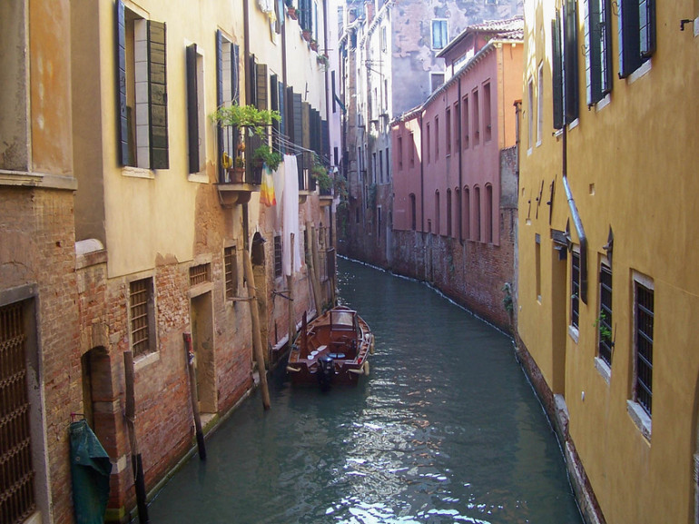a small water channel in Venice, with houses and boats