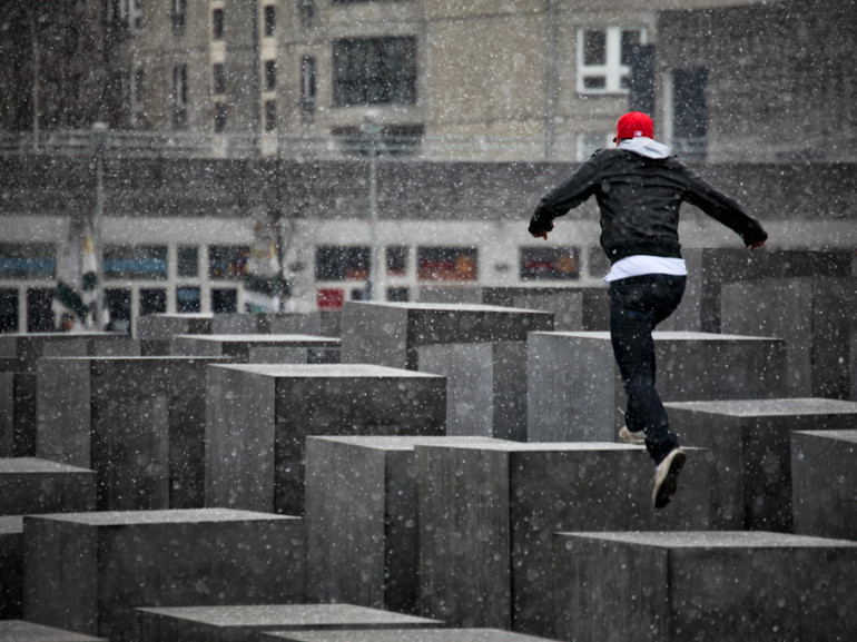 a guy walking on squared rocks while it is snowing