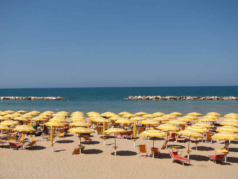 Seaside: many yellow umbrellas in the sand and the sea