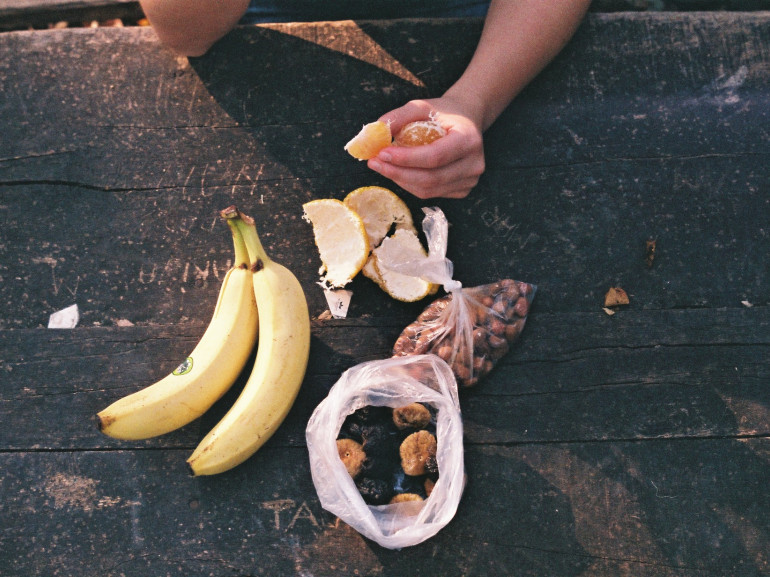 on a table made of wooden a banana and other fruits. a guy is eating