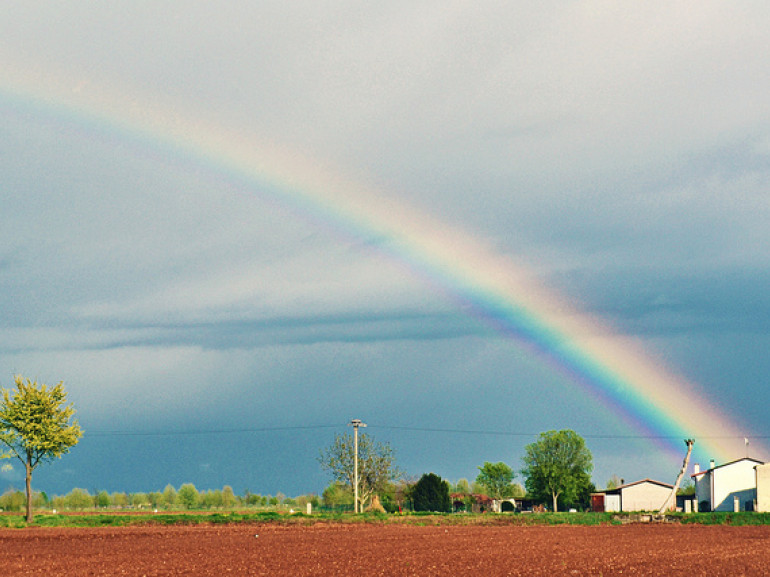 flat land, a country house and the rainbow in the sky