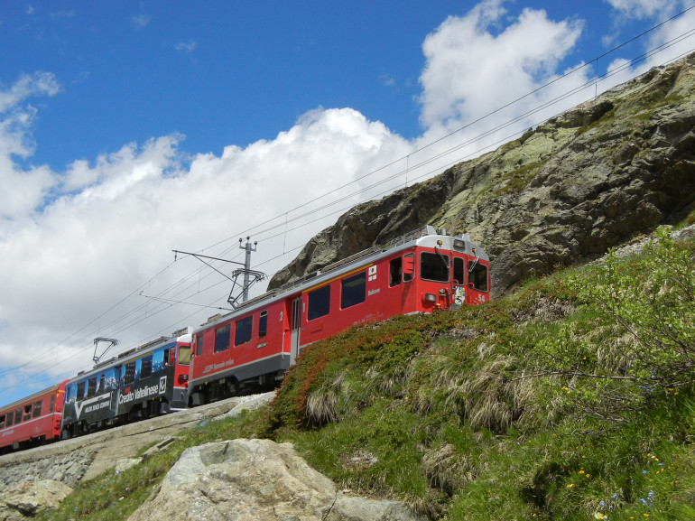 a red train crossing the mountains