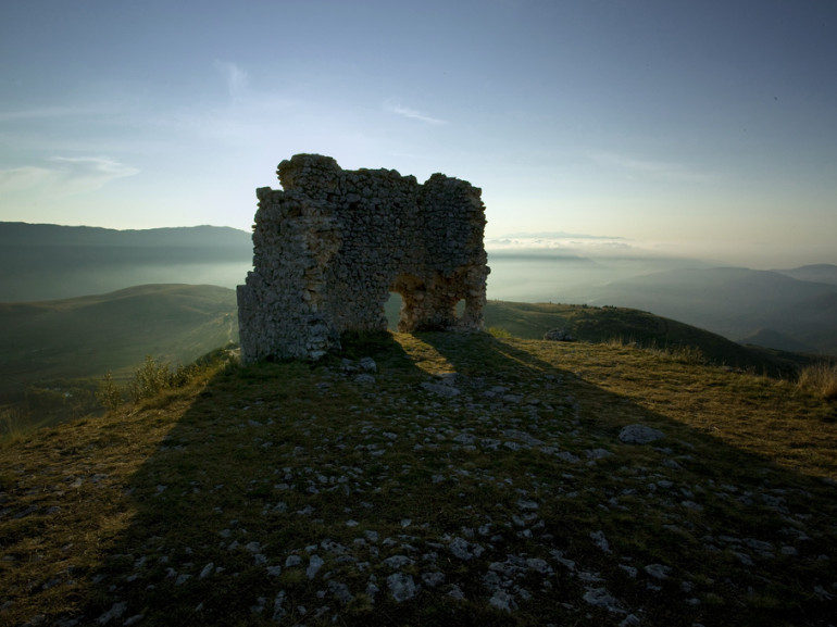 a rocky tower on a hill at the sunset