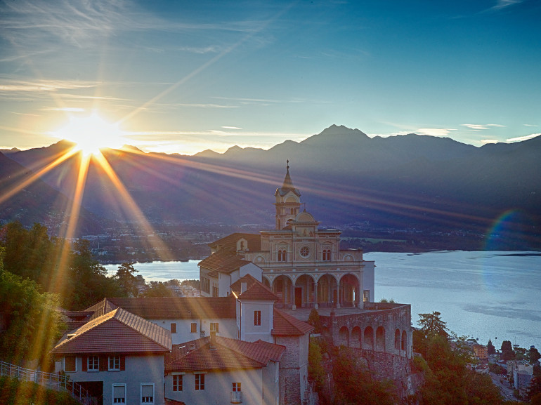 locarno lake seen from the top of an hill where a church stands in the morning light