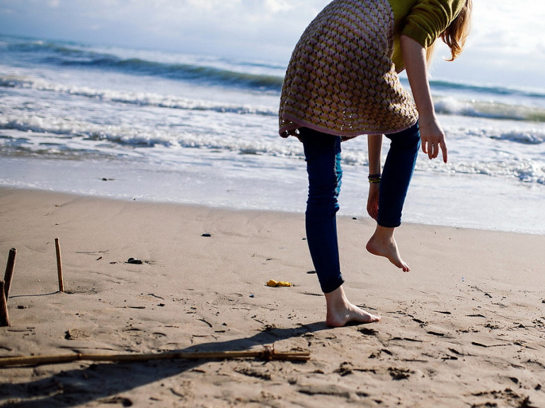 sandy seaside with a girl walking on it