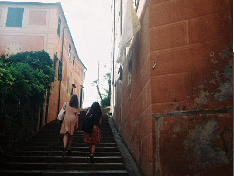 Two girls are going up the stairs in the historical centre of Camogli