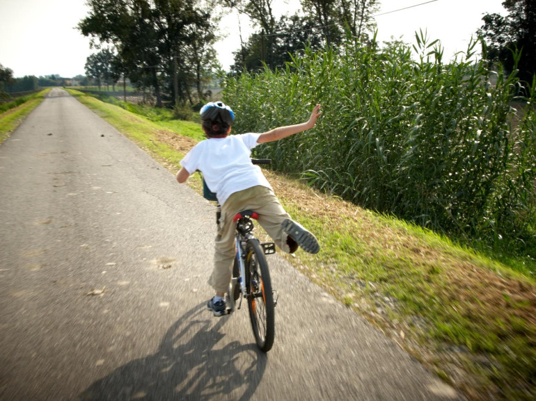 A child on a bicycle along a path near the river