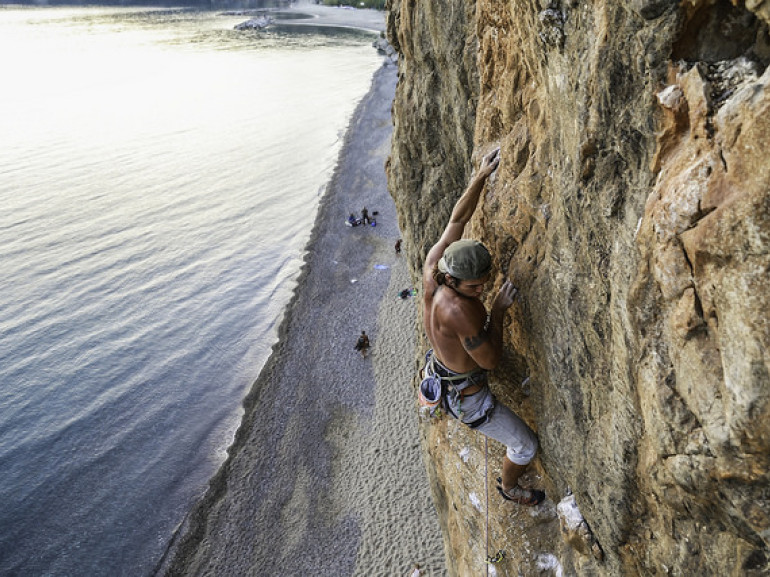 a climber on a rocky cliff near the sea