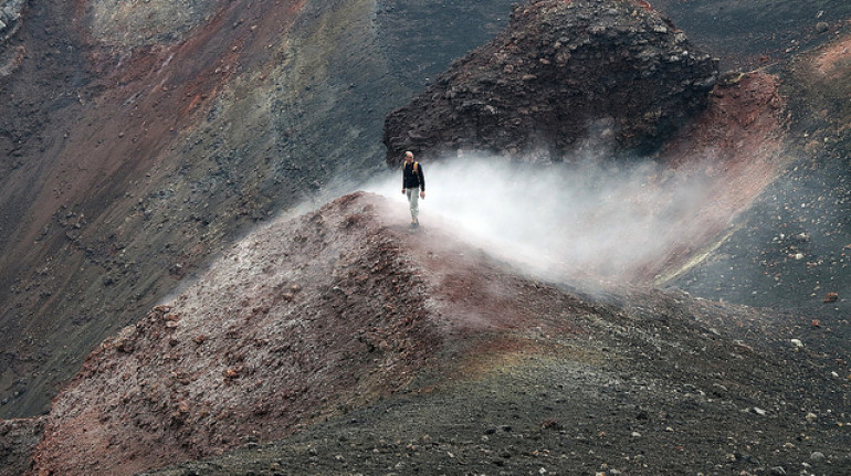 The black slope of the volcano and a hicker walking trough it